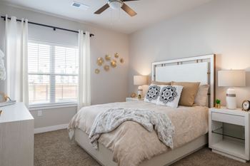 A bedroom with a large bed and a ceiling fan.